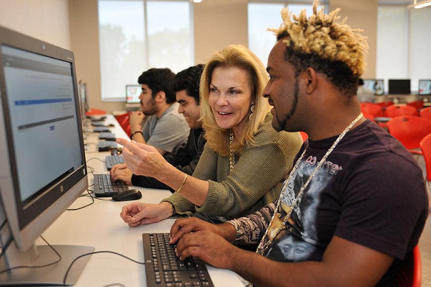 student in front of computer being assisted by union employee